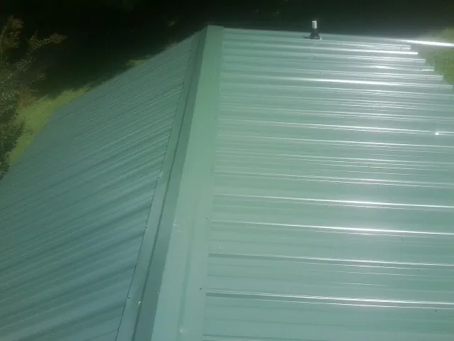 New green metal panels meeting at the ridge of a roof — Flat Roof Repair work by our crew in Lamona