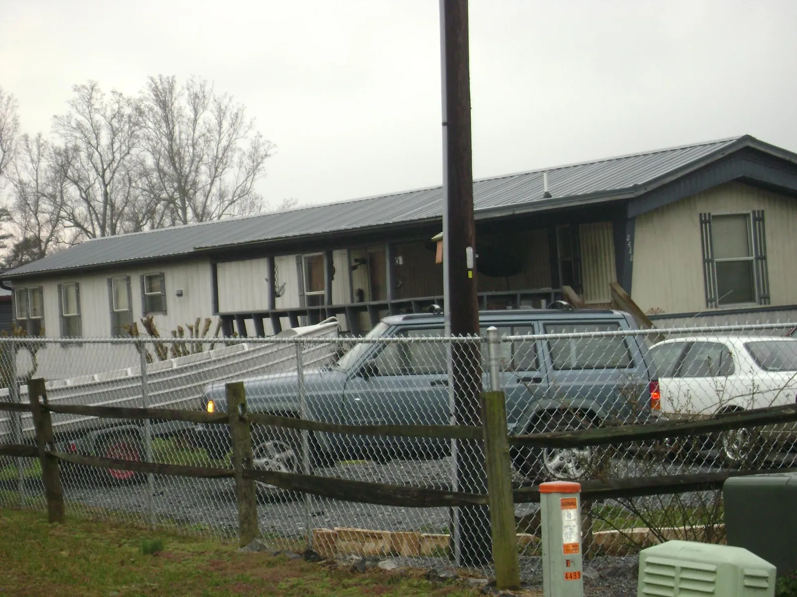Dark metal roof on a long single story building behind a chain link fence in Lamona