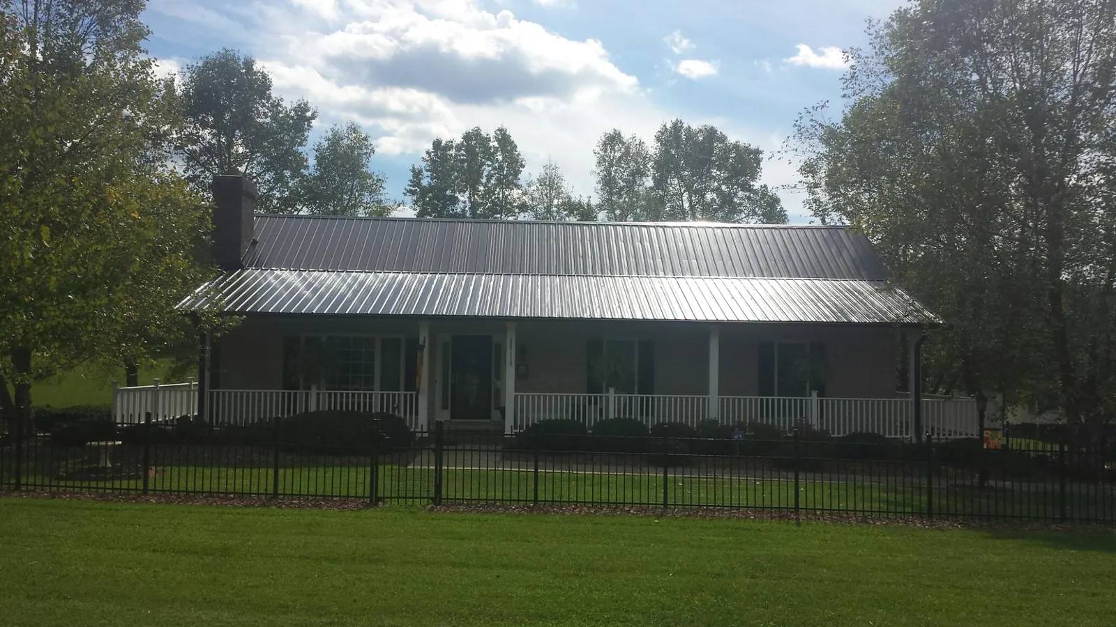 Gray metal roof on a brick ranch with a full width front porch — Gutter Guard Installation work by our crew in Lamona