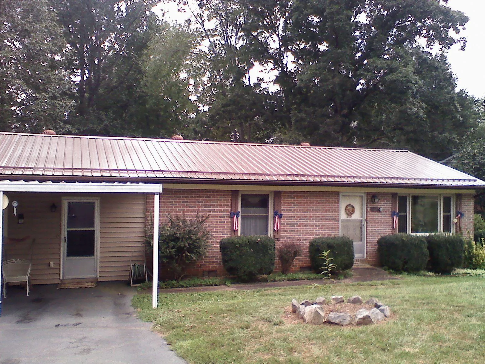 Bronze metal roof and carport on a brick ranch home — Roof Repair work by our crew in Lamona