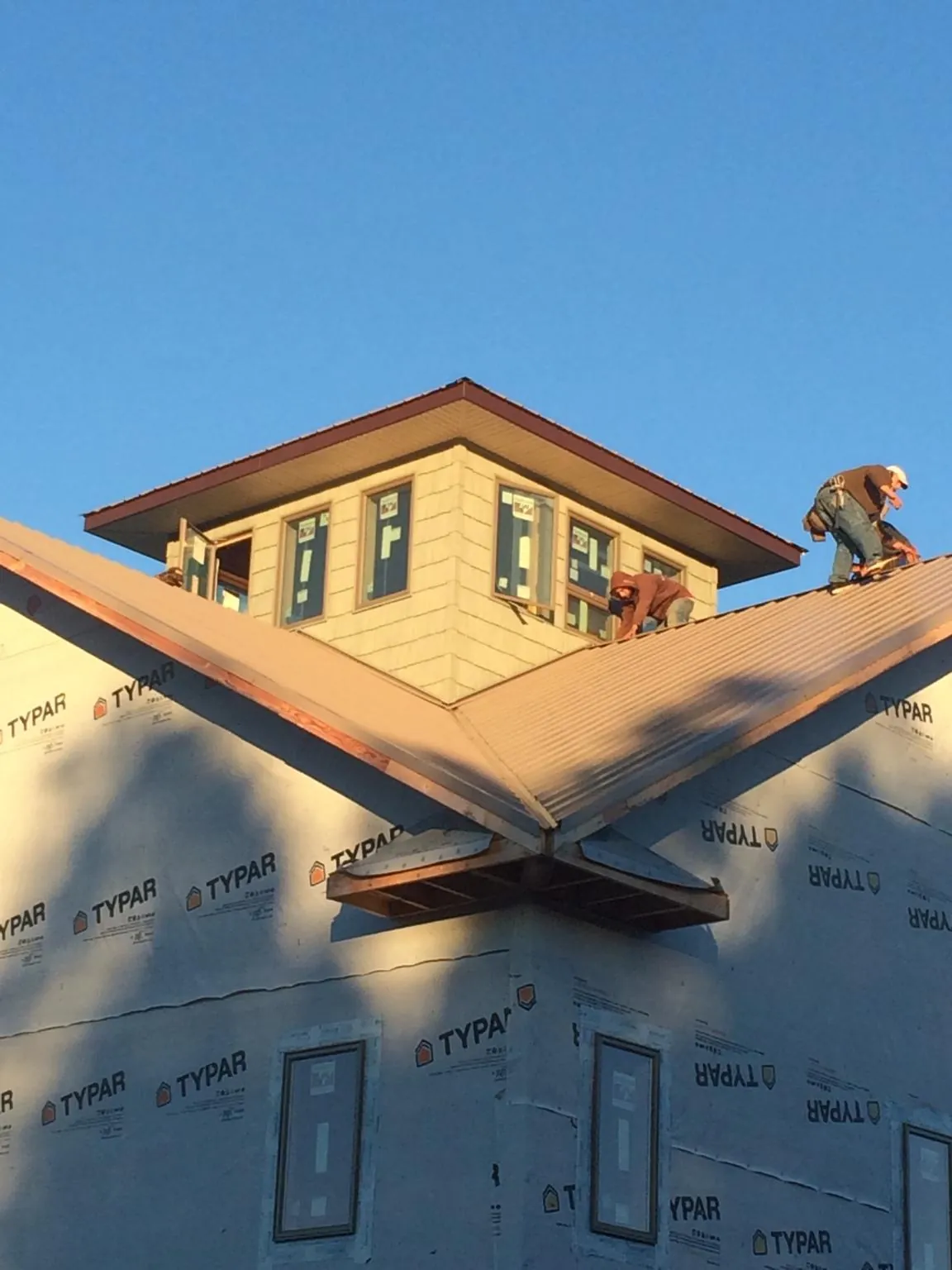 Roofers working around a rooftop cupola on a new metal roof at sunset — Roof Waterproofing in Lamona by Roofing Brothers